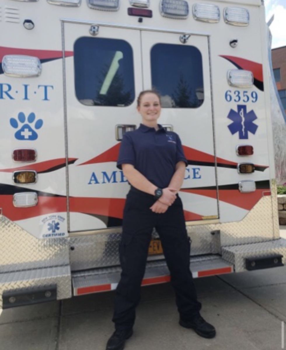 Student EMT posing behind ambulance