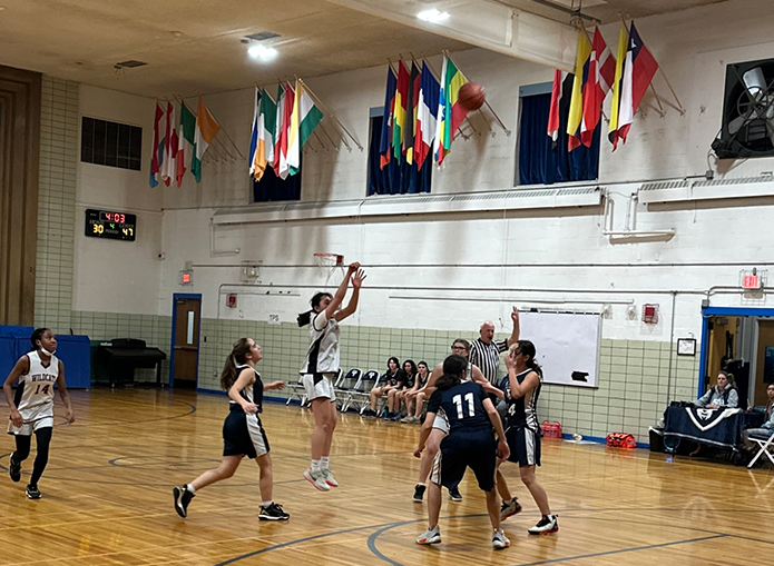 Woodward basketball player airborne for a 3 point shot as other players look on