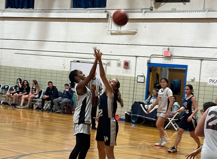 2 basketball players attempt to catch the ball in motion