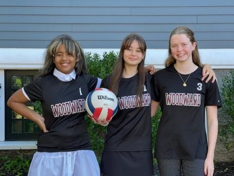 photo of 3 Woodward volleyball players posing near the blue house