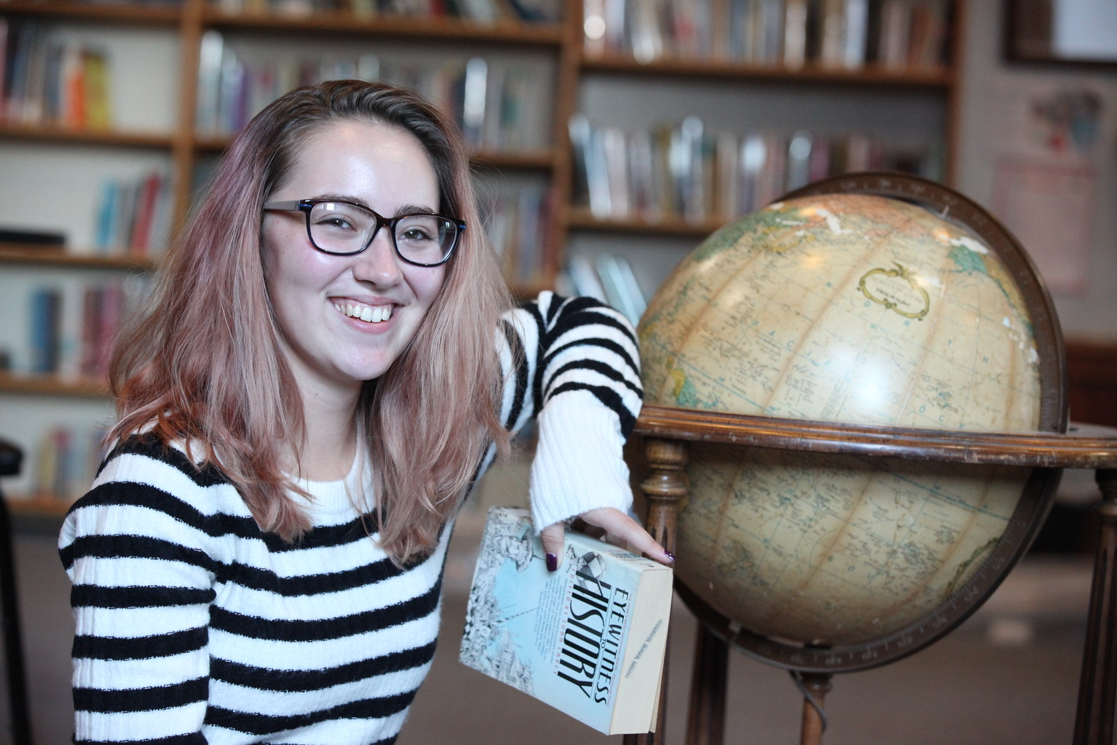 Woodward student poses with book and globe